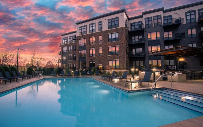 a pool in front of a building with a sunset