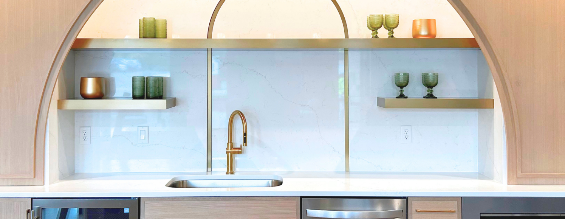 Community kitchen featuring appliances, sink and shelving above holding green and orange glasses